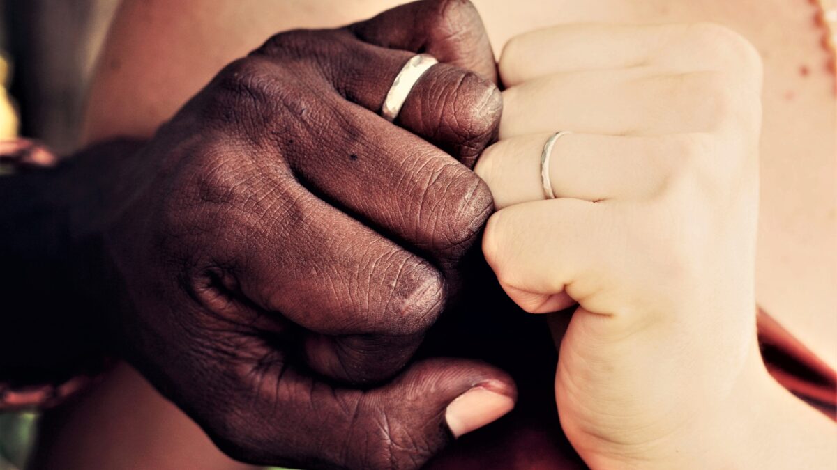 Mixed couple showing wedding ring fingers in close up