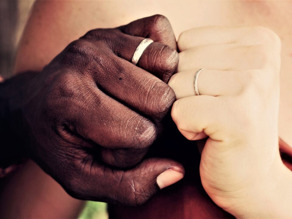 Mixed couple showing wedding ring fingers in close up