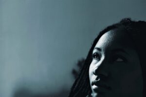 Black and white photo of black woman looking up - moody and reflective. 