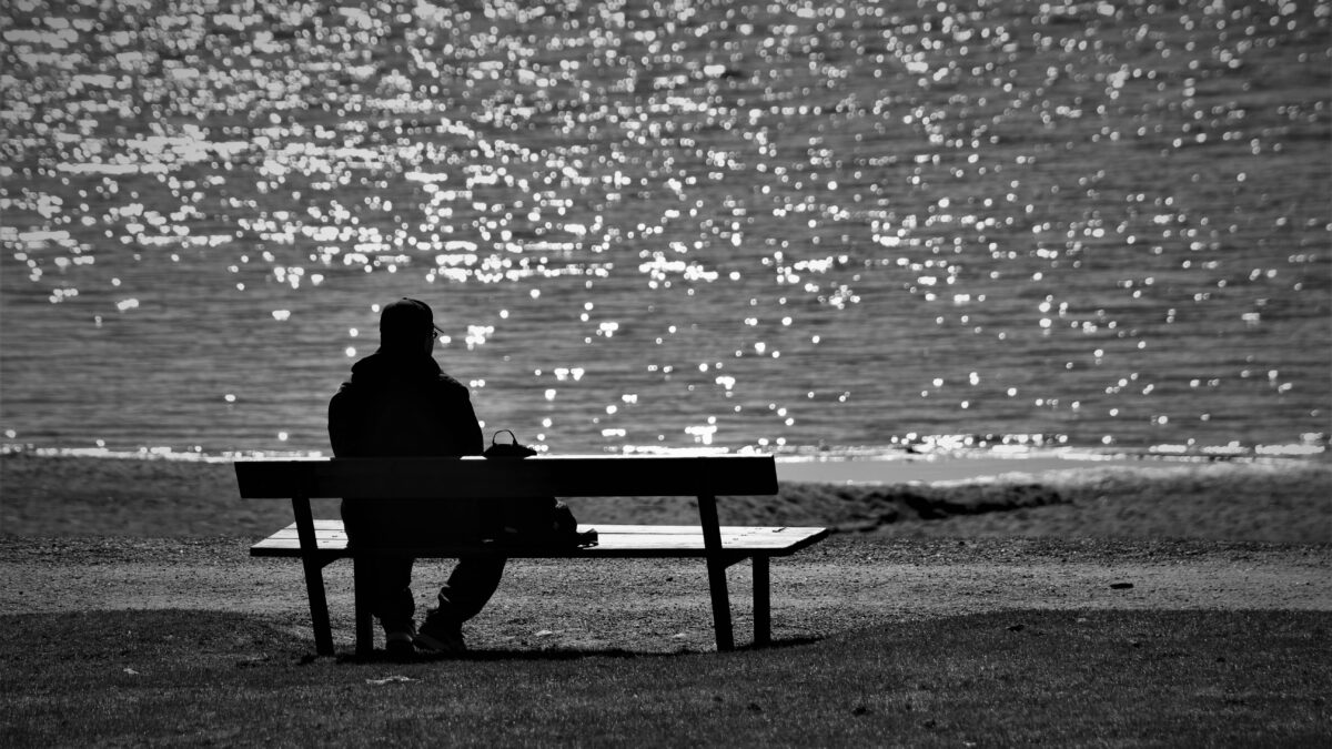 Man on bench looking out to ocean.