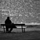 Man on bench looking out to ocean.