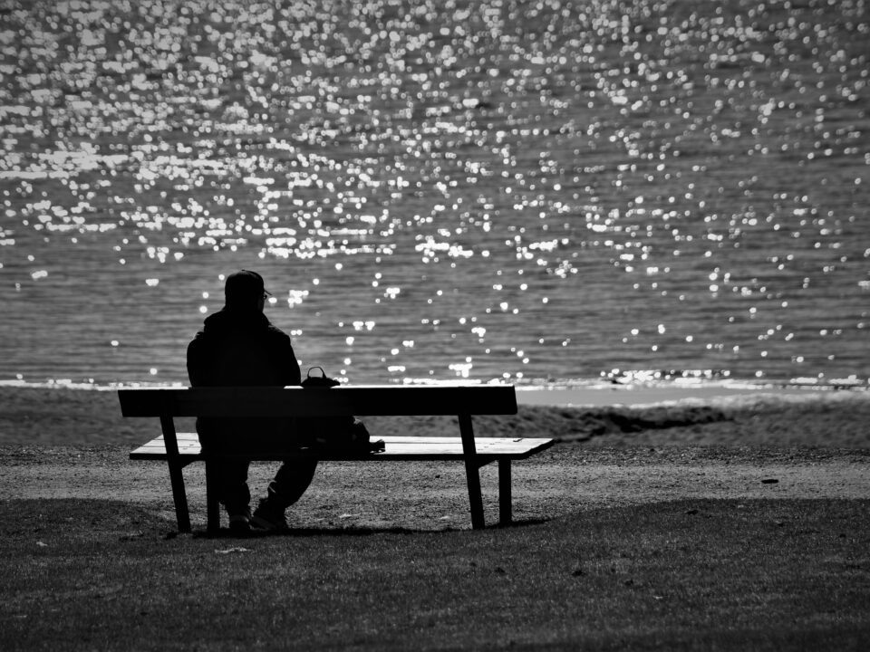 Man on bench looking out to ocean.
