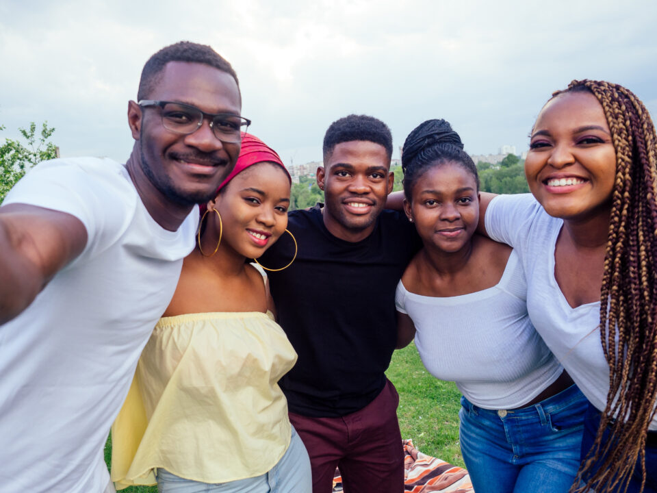 group of five friends female and male taking selfie on camera smartphone and having fun outdoors lifestyle near lake